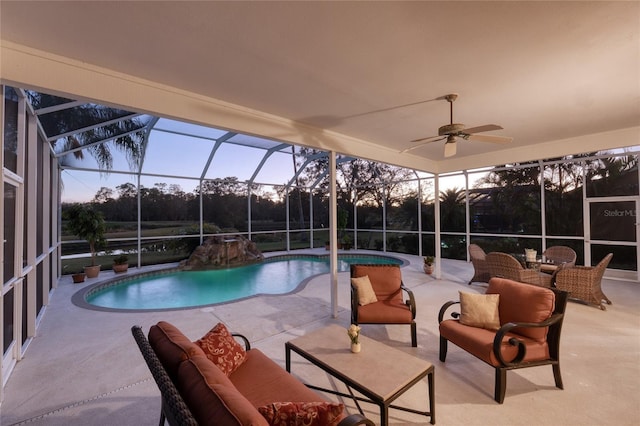 pool at dusk featuring outdoor lounge area, a patio, ceiling fan, and a lanai