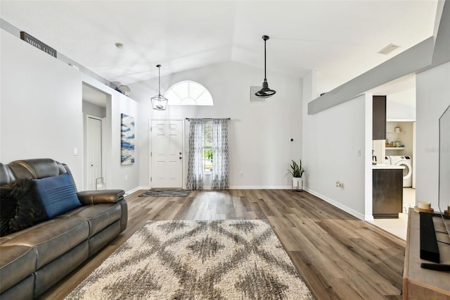 living room with washer / dryer, hardwood / wood-style flooring, and lofted ceiling