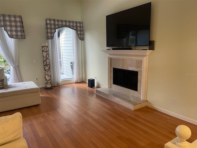 unfurnished living room featuring hardwood / wood-style flooring, a healthy amount of sunlight, and a tile fireplace