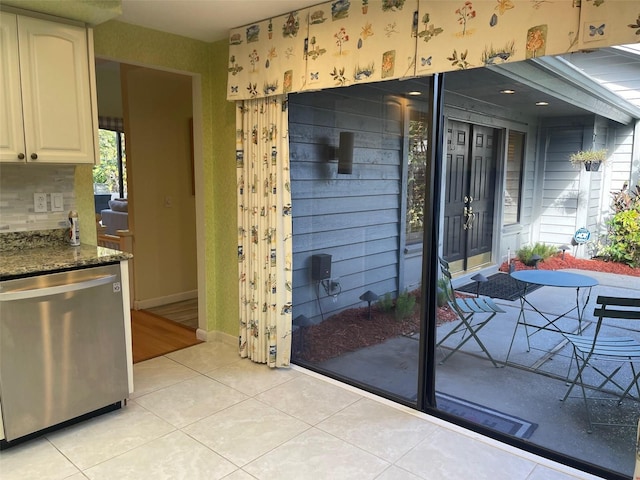 exterior space featuring white cabinetry, dishwasher, tasteful backsplash, dark stone counters, and light tile patterned floors