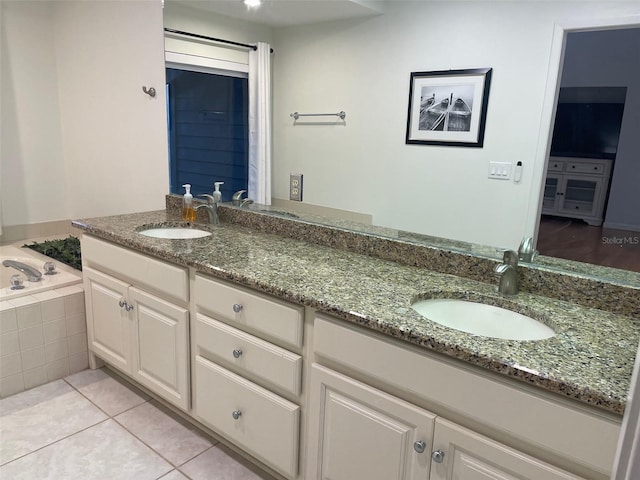 bathroom featuring tile patterned flooring, vanity, and tiled bath