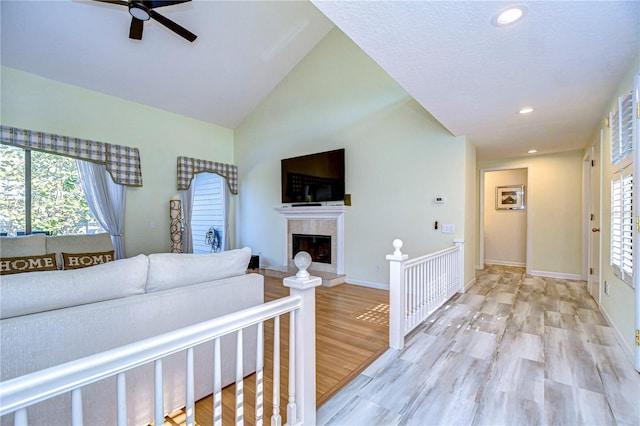 living room featuring ceiling fan, light hardwood / wood-style floors, and lofted ceiling