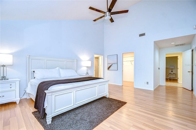 bedroom with high vaulted ceiling, ceiling fan, a spacious closet, light hardwood / wood-style floors, and a closet