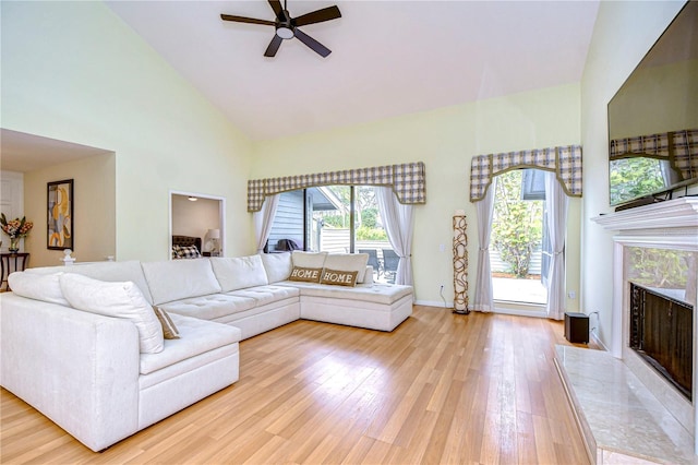 living room with a fireplace, high vaulted ceiling, light hardwood / wood-style flooring, and ceiling fan