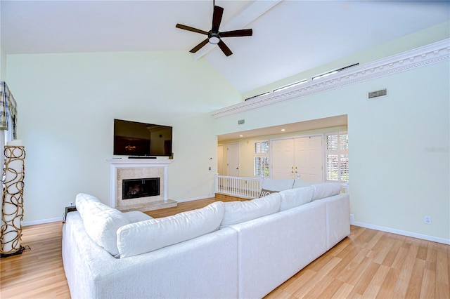 living room with light wood-type flooring, high vaulted ceiling, ceiling fan, and a tiled fireplace