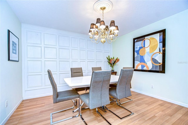 dining area with light wood-type flooring and an inviting chandelier