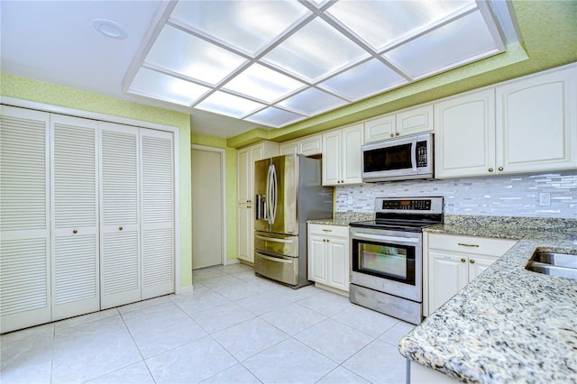 kitchen with white cabinets, light stone countertops, backsplash, and appliances with stainless steel finishes