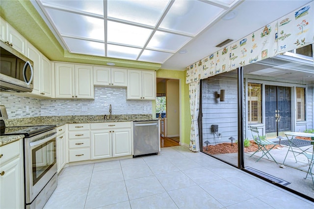 kitchen with white cabinets, appliances with stainless steel finishes, light stone countertops, and sink