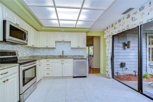 kitchen featuring white cabinets, sink, light tile patterned floors, light stone counters, and stainless steel appliances