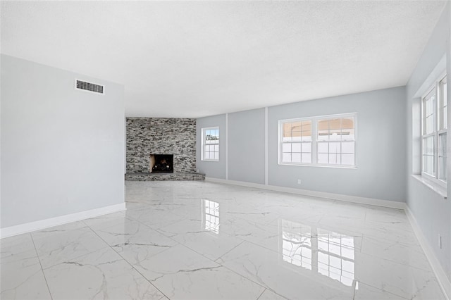 unfurnished living room with a stone fireplace and a textured ceiling