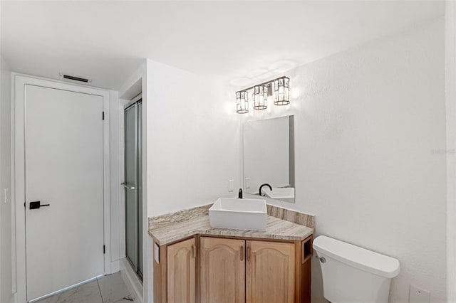 bathroom featuring tile patterned flooring, vanity, an enclosed shower, and toilet