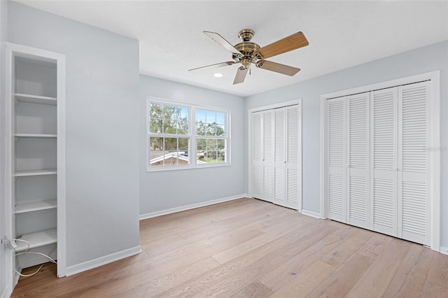 unfurnished bedroom with ceiling fan, light hardwood / wood-style flooring, and two closets