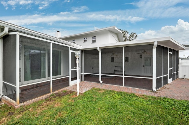 back of property with a lawn and a sunroom