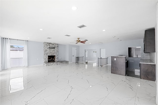 unfurnished living room featuring ceiling fan and a fireplace