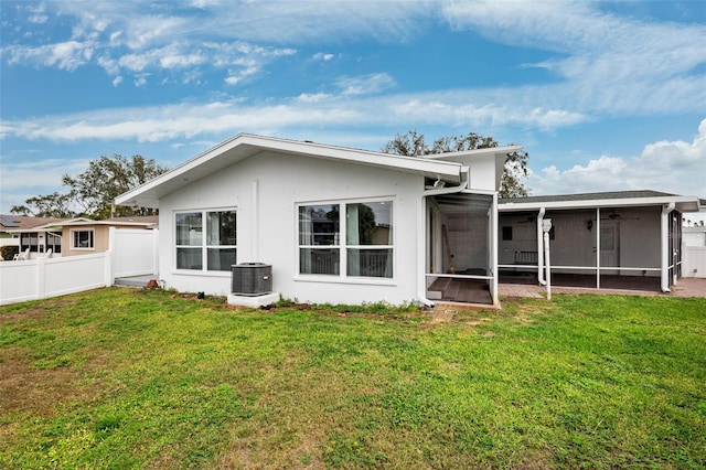 back of property featuring central air condition unit, a lawn, and a sunroom