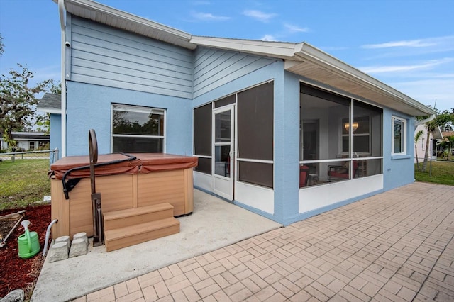 back of house featuring a sunroom, a patio area, and a hot tub