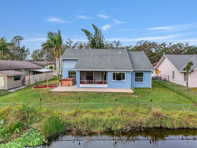 rear view of house with a yard, a water view, a patio, and a hot tub