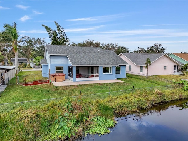 back of house with a yard, a water view, a patio, and a hot tub