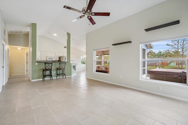 unfurnished living room with ceiling fan, light tile patterned floors, and vaulted ceiling