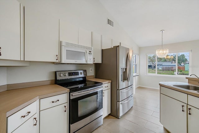 kitchen featuring white cabinets, stainless steel appliances, hanging light fixtures, and an inviting chandelier