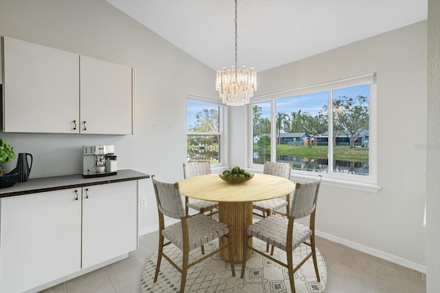 tiled dining area featuring a chandelier, a water view, vaulted ceiling, and plenty of natural light