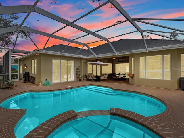 pool at dusk featuring a patio and a lanai