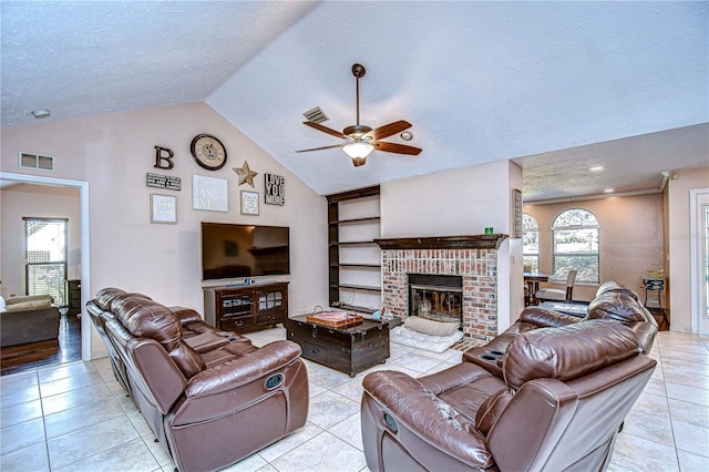 living room featuring ceiling fan, light tile patterned flooring, a textured ceiling, and a brick fireplace