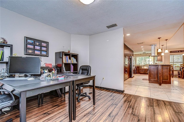 office space featuring light wood-type flooring and a textured ceiling