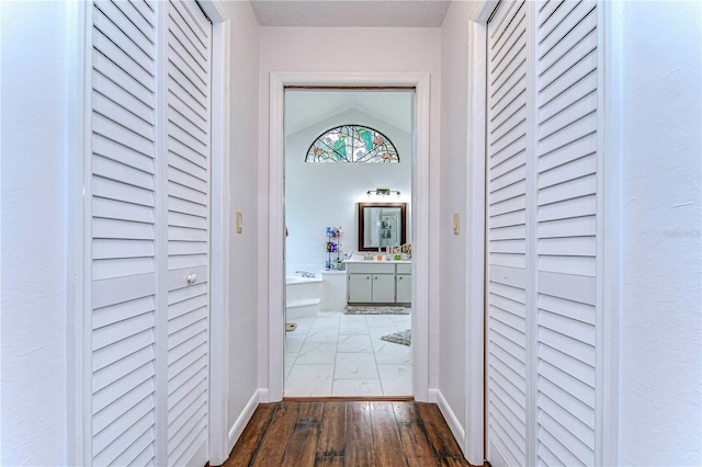 corridor with light hardwood / wood-style floors and vaulted ceiling