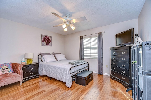 bedroom with ceiling fan, a textured ceiling, and light hardwood / wood-style flooring