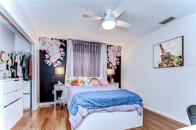 bedroom featuring ceiling fan, light wood-type flooring, a textured ceiling, and a closet