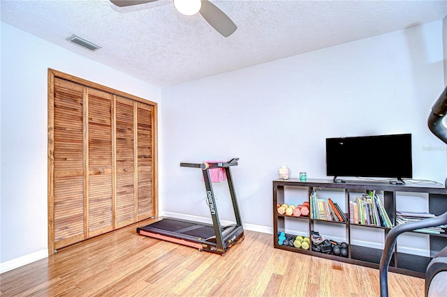 exercise area with wood-type flooring, a textured ceiling, and ceiling fan