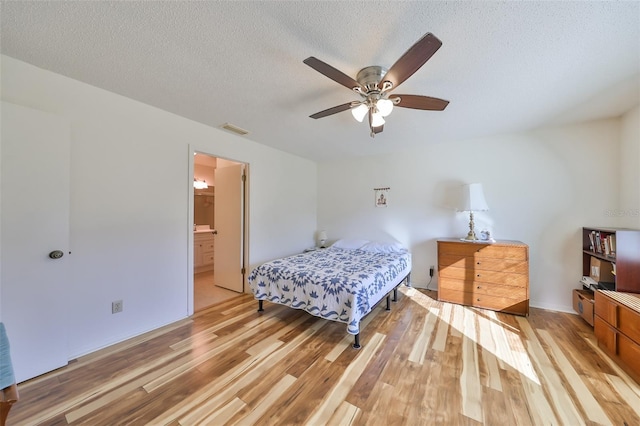 bedroom with a textured ceiling, ensuite bathroom, ceiling fan, and light hardwood / wood-style floors