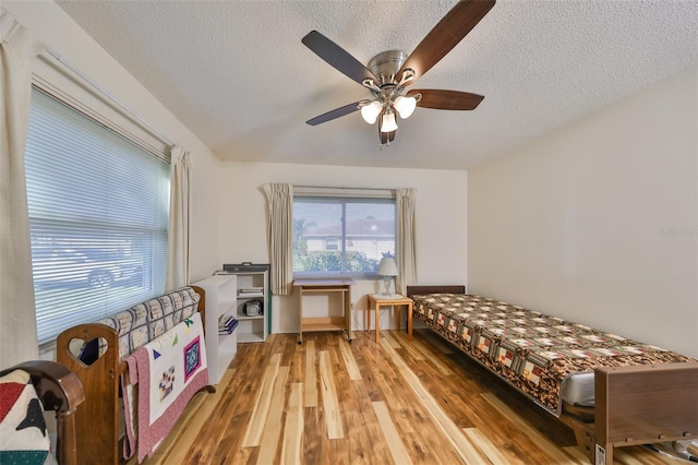 bedroom featuring ceiling fan, wood-type flooring, and a textured ceiling