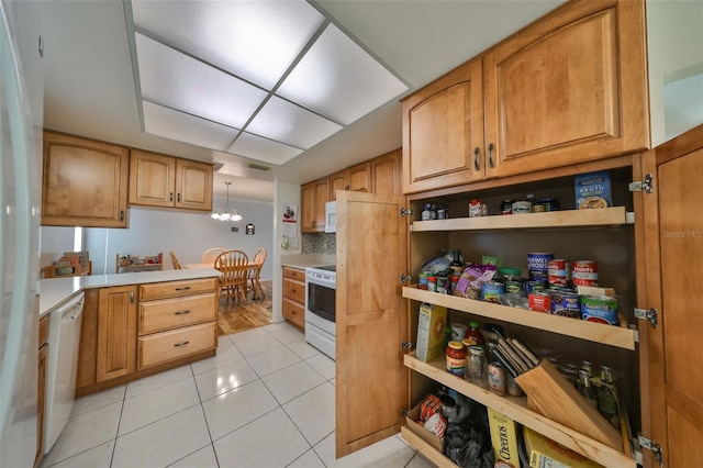 kitchen featuring hanging light fixtures, tasteful backsplash, a chandelier, white appliances, and light tile patterned floors