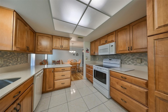 kitchen with kitchen peninsula, backsplash, white appliances, light tile patterned floors, and decorative light fixtures