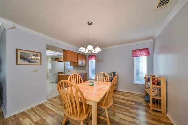 dining room featuring crown molding, sink, a chandelier, and light wood-type flooring