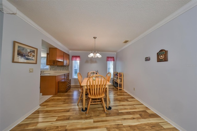 dining space featuring light hardwood / wood-style floors, a healthy amount of sunlight, ornamental molding, and a chandelier