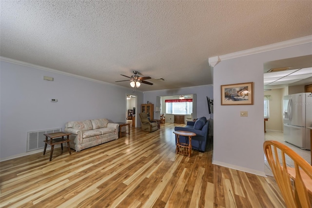 living room featuring a textured ceiling, light hardwood / wood-style floors, ceiling fan, and crown molding