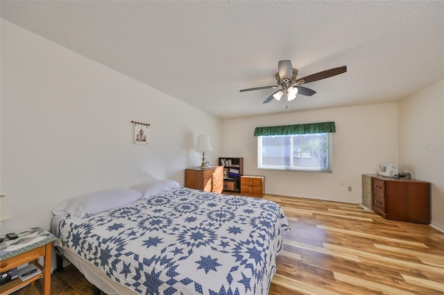 bedroom featuring ceiling fan, light hardwood / wood-style flooring, and a textured ceiling