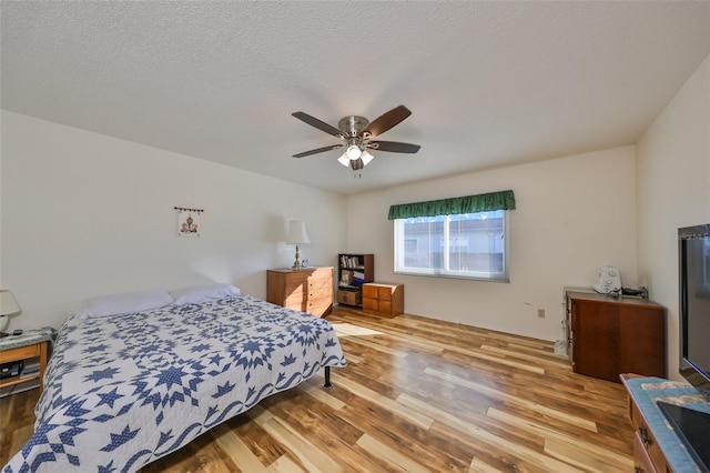 bedroom featuring ceiling fan, a textured ceiling, and light wood-type flooring