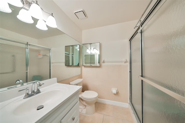 bathroom featuring toilet, vanity, tile patterned floors, and a shower with shower door