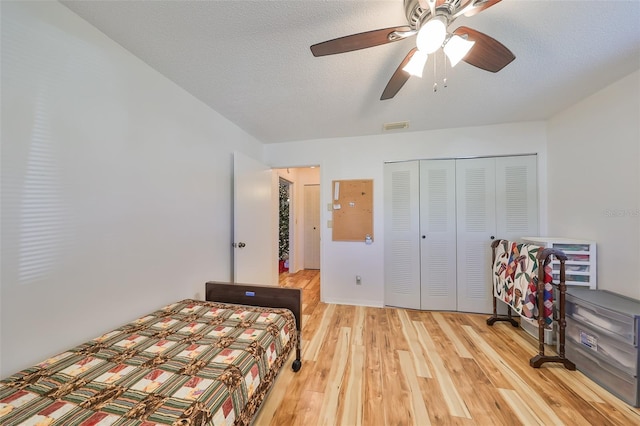 bedroom featuring ceiling fan, a closet, light hardwood / wood-style floors, and a textured ceiling