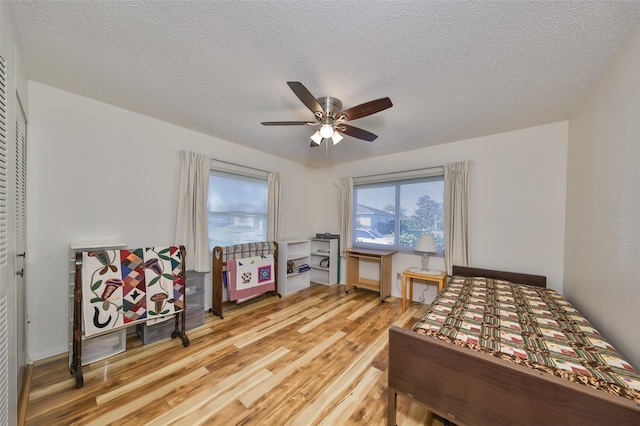 bedroom featuring hardwood / wood-style flooring, ceiling fan, and a textured ceiling