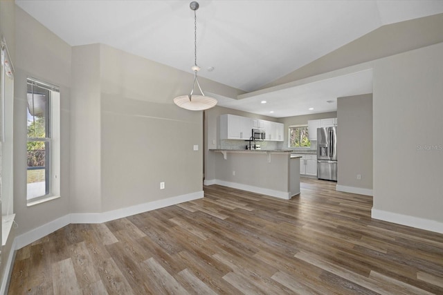 unfurnished living room with hardwood / wood-style floors and vaulted ceiling