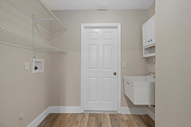 clothes washing area with hookup for a washing machine, sink, cabinets, and light wood-type flooring