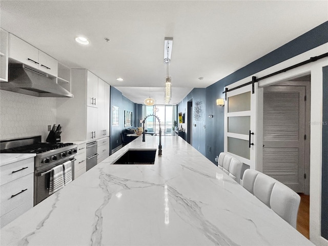 kitchen with white cabinetry, sink, hanging light fixtures, a barn door, and high end stove