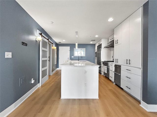 kitchen featuring white cabinetry, a barn door, an island with sink, pendant lighting, and high end appliances