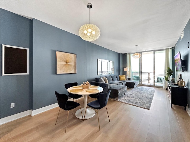 dining area with floor to ceiling windows, light hardwood / wood-style flooring, and a chandelier