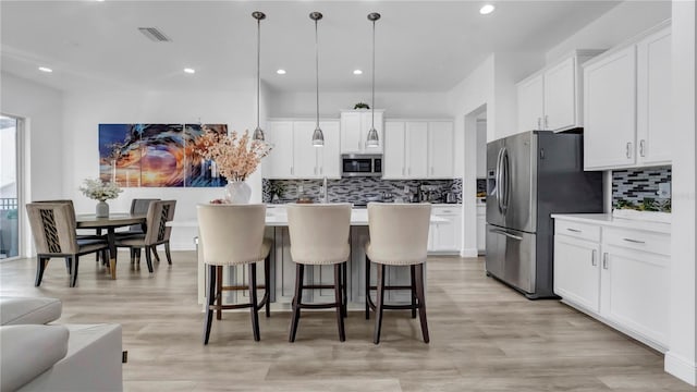 kitchen with decorative light fixtures, white cabinetry, and stainless steel appliances